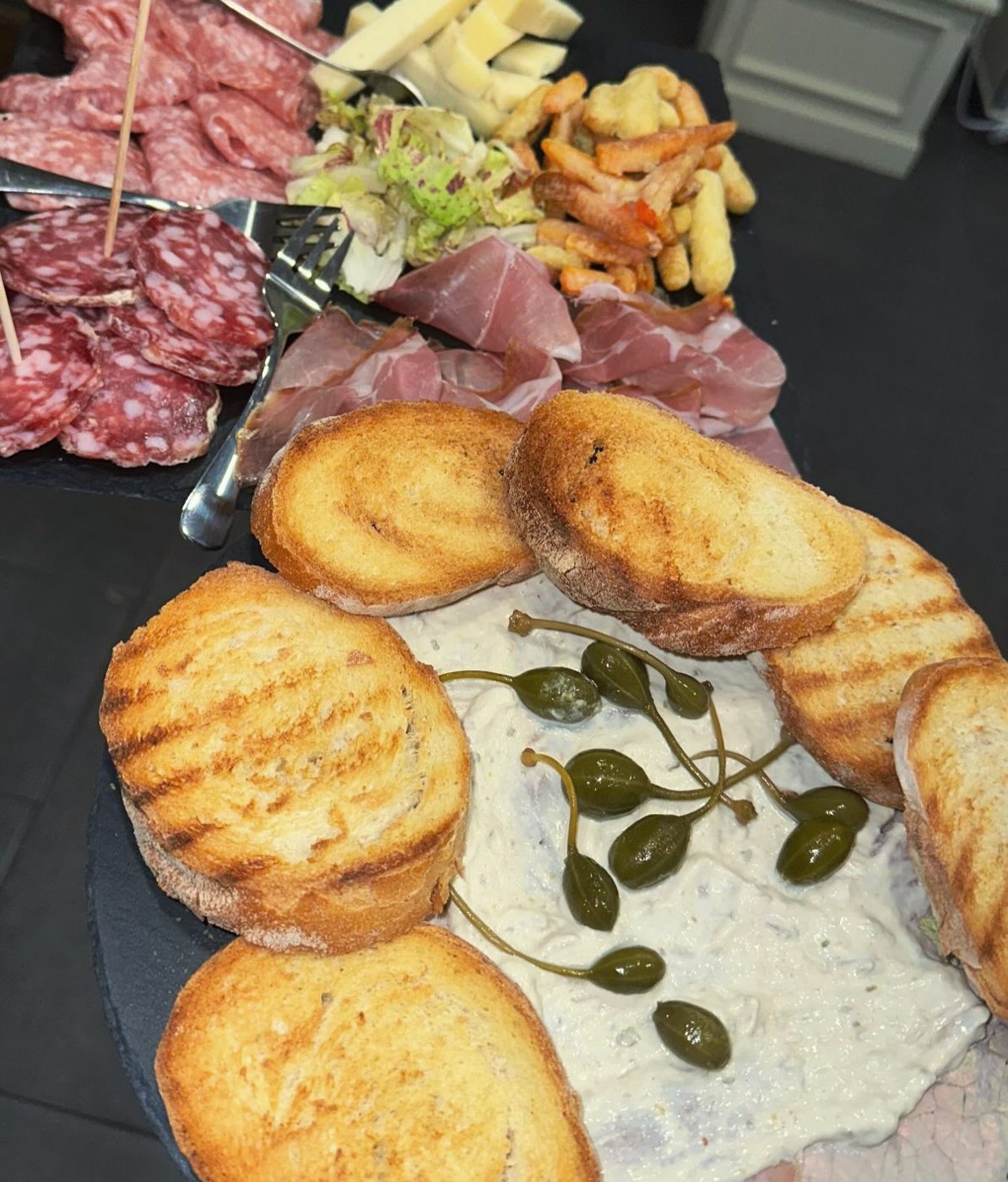 Tagliere con salumi, formaggi, crostini e capperi